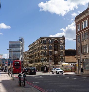 Southwark caddesinde büyük pencereli eski tuğla bina. Binanın arkasında gökyüzü parlak mavi ve üzerinde de birkaç bulut yüzüyor..