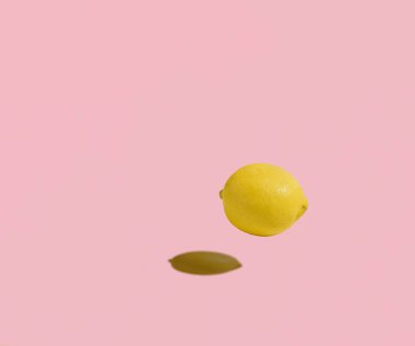  Pastel pembe arka planda yüzen izole bir limon. Kopyalama alanı, minimum meyve konsepti. Sağlıklı, dengeli beslenme.
