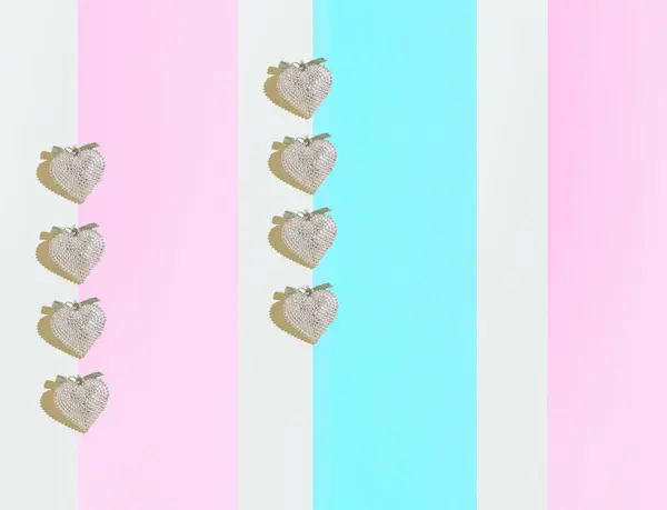 A pattern made of silver hearts against the wallpaper background.Pink, blue and white background. Minimal concept of love. Flat lay. Valentines card pattern.