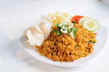 Nasi Goreng 'e dilimlenmiş taze soğan serpiştirilmiş sığır gözü yumurtası ve sebze servis edilir.