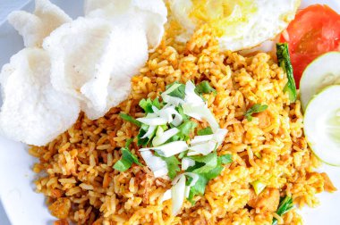 Kızarmış pirinç, dana gözlü yumurta, kraker ve dilimlenmiş taze soğanla servis ediliyor.