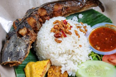 Kızarmış yayın balığı, beyaz pirinç, kızarmış tempeh tofu ve özel baharatlı biber sosu ile servis edilir.