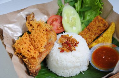 Beyaz pirinç ve kızarmış tempeh tofu ile servis edilen Ayam Goreng kremleri ve özel baharatlı acı biber sosu.