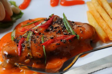 Salata ve patates kızartmasıyla servis edilen sosa batırılmış biftek.