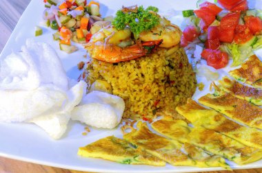 Omlet, turşu ve krakerle servis edilen kızarmış karidesli leziz pilav..