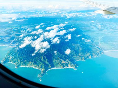 Deniz kenarındaki bir ada, uçak penceresinin arkasından görülebiliyor.