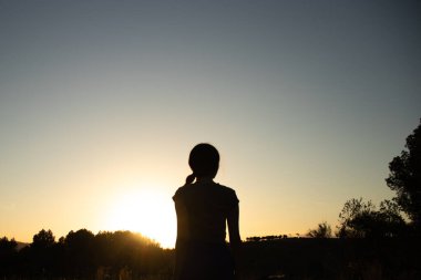 İspanya 'nın Barselona yakınlarındaki İspanyol köyü El Papiol' de yaz yürüyüşü yapan genç ve güzel bir kadının silueti.  