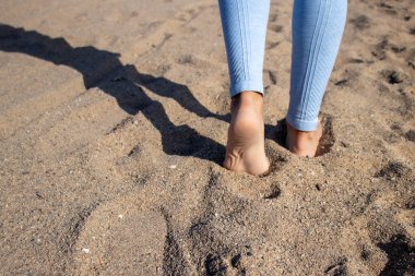Genç dişi çıplak ayakla deniz kenarında egzersiz yapıyor, Barselona, İspanya 'da dişi bacaklarını kapatıyor. 