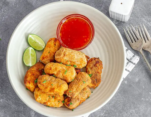 Limonlu kızarmış balık çubukları ve üzerine de taze maydanozla süslenmiş sos.