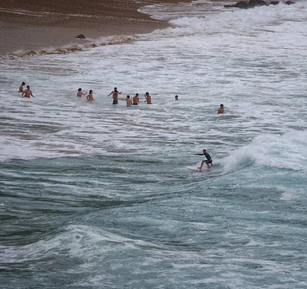 İnsanlar denizde sörf tahtası kullanıyorlar.