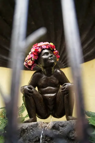 Kafasında çiçek tacı olan bir adamın heykeli.