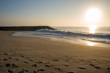 Kumsalda ayak izleri ve batan bir güneş.