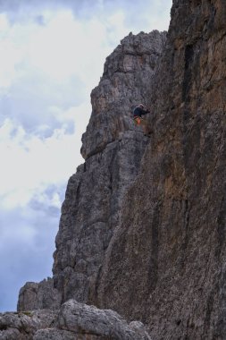 Sırt çantasıyla dik bir dağa tırmanan bir adam.
