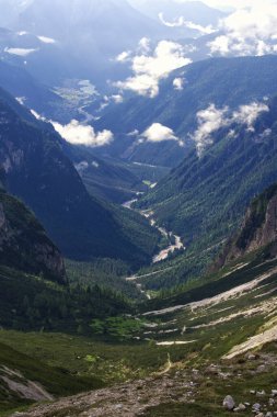 Arkasında birkaç ağaç ve dağ olan bir vadi.