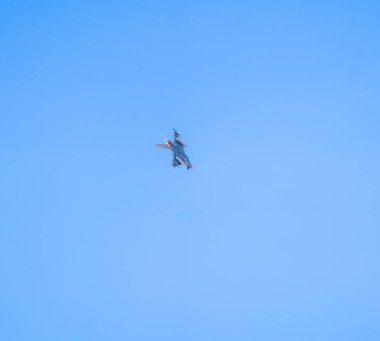 Mavi gökyüzüne karşı uçan bir uçak.