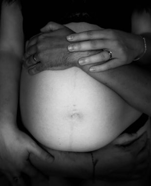 Hamile kadın ve erkek göbeğinin elini tutuyor.