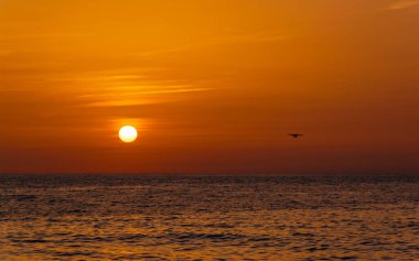 Deniz üzerinde gün batımı ve bir uçak