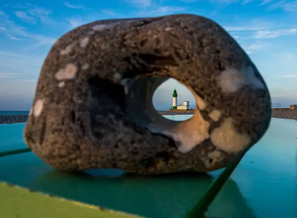 Taştaki delikten bir deniz fenerine bak.