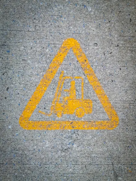 Image of a forklift driver in a yellow triangle on a cement road