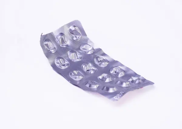 Kullanılmış bir su toplayıcısının yakın plan fotoğrafı. Hapların daha önce bulunduğu girintili şekilleri gösteriyor. Paket biraz buruşmuş ve metalik bir parıltısı var..