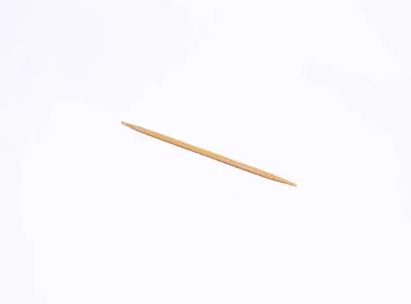 Tek bir kürdan beyaz arka planda dümdüz yatıyordu. Kürdan tahtadan yapılmış ve ucu sivri..