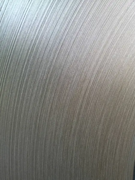 Dikey kaba dokuya sahip gümüş paslanmaz çelik bir levhanın yakın çekimi. İnce çizgiler ve oyuklar, maddenin endüstriyel ve estetik çekiciliğini vurgulayan karmaşık bir kalıp oluşturuyor..