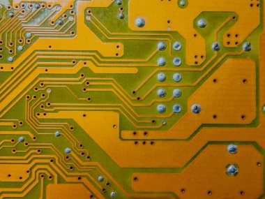 Yazılı devre kartının yakın plan fotoğrafı, karmaşık yeşil ve sarı izlerini ve lehim noktalarını gösteriyor, teknoloji ve elektronik temalar için ideal..