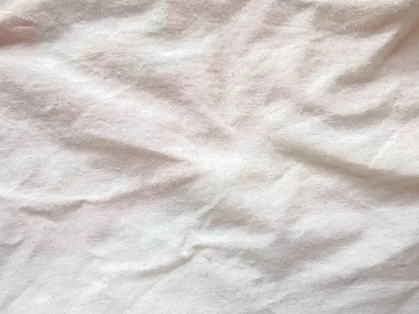 Yumuşak, buruşuk yüzeyi, tasarım, tekstil veya minimalist dekor temaları için ideal olan beyaz kumaşın dokulu bir arka planı.