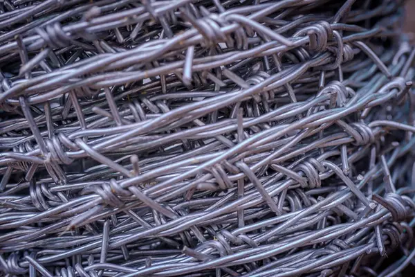 Keskin, bükülmüş metal dokusunu gösteren dikenli tellerin yakın plan fotoğrafı güvenlik, sınırlar veya endüstriyel tasarım temaları için idealdir..