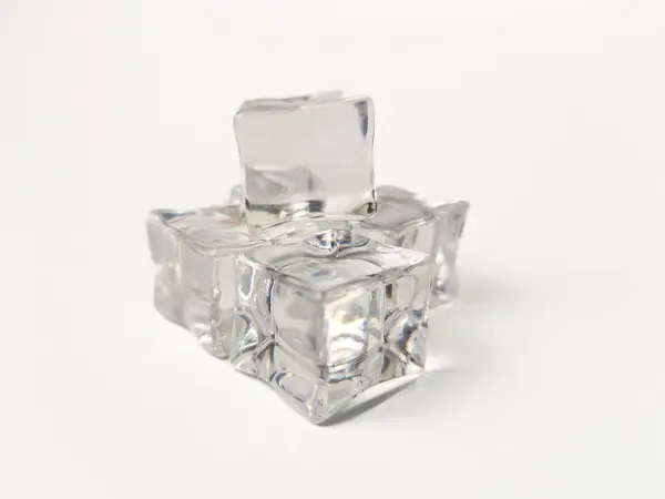 Beyaz zemin üzerine yığılmış saydam buz küpleri yakın plan, berraklık, yansımalar ve canlandırıcı estetik sergiliyor