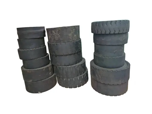 Beyaz arka planda izole edilmiş eskimiş bir forklift lastiğinin yüksek çözünürlüklü yakın çekimi. Ayrıntılı dokular ve engebeli lastik desenleri, ağır kullanım ve endüstriyel giyimin işaretlerini vurguluyor.