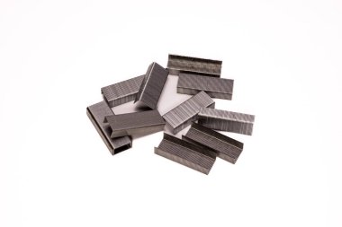 Temiz beyaz arka planda metal zımbalardan oluşan bir makro yakın plan. Keskin kenarlar, pürüzsüz yüzey ve endüstriyel doku ofis, arz ve minimalist tasarım temaları için idealdir..