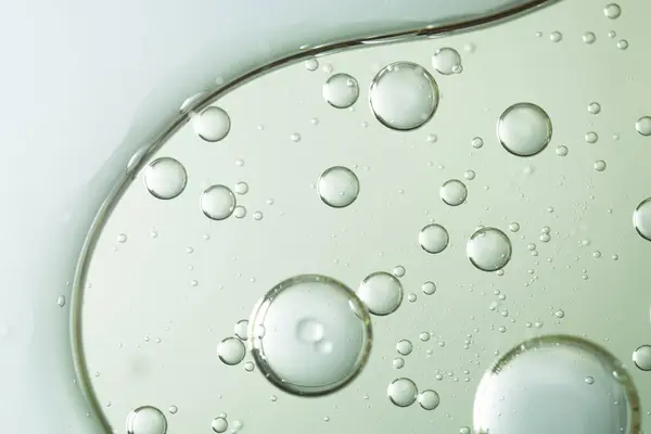 Yüzdeki serumun dokusunu çağrıştıran, berrak bir sıvıda asılı duran yağ kabarcıklarının makro soyut bir görüntüsü. Güzellik, kozmetik ve cilt temalı görseller için ideal.