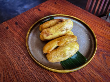 Tahta bir masada bir tabak kızarmış muz, muz ve kızarmış muzla kaplanmış tipik bir Endonezya atıştırması..