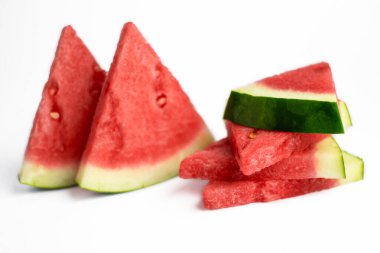 Çekirdeksiz kırmızı karpuz dilimleri beyaz zemin üzerinde izole edilmiş ve geniş bir alana yayılmış..