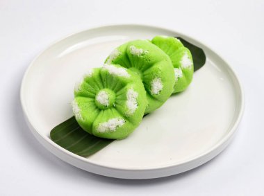 Kue Putu Ayu, pirinç unu, pandan yaprağı ve rendelenmiş hindistan cevizi veya palmiye şekerinden yapılan geleneksel Endonezya keki. Beyaz arka planı olan beyaz bir tabakta servis edilir..