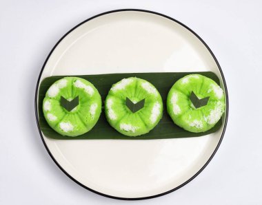 Kue Putu Ayu, pirinç unu, pandan yaprağı ve rendelenmiş hindistan cevizi veya palmiye şekerinden yapılan geleneksel Endonezya keki. Beyaz arka planı olan beyaz bir tabakta servis edilir..