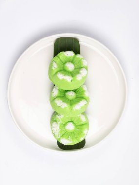 Kue Putu Ayu, pirinç unu, pandan yaprağı ve rendelenmiş hindistan cevizi veya palmiye şekerinden yapılan geleneksel Endonezya keki. Beyaz arka planı olan beyaz bir tabakta servis edilir..