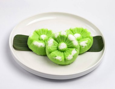 Kue Putu Ayu, pirinç unu, pandan yaprağı ve rendelenmiş hindistan cevizi veya palmiye şekerinden yapılan geleneksel Endonezya keki. Beyaz arka planı olan beyaz bir tabakta servis edilir..