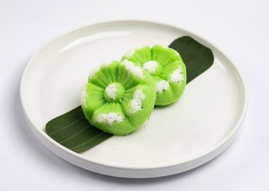 Kue Putu Ayu, pirinç unu, pandan yaprağı ve rendelenmiş hindistan cevizi veya palmiye şekerinden yapılan geleneksel Endonezya keki. Beyaz arka planı olan beyaz bir tabakta servis edilir..