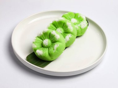 Kue Putu Ayu, pirinç unu, pandan yaprağı ve rendelenmiş hindistan cevizi veya palmiye şekerinden yapılan geleneksel Endonezya keki. Beyaz arka planı olan beyaz bir tabakta servis edilir..