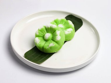 Kue Putu Ayu, pirinç unu, pandan yaprağı ve rendelenmiş hindistan cevizi veya palmiye şekerinden yapılan geleneksel Endonezya keki. Beyaz arka planı olan beyaz bir tabakta servis edilir..