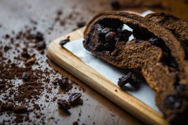 Lezzetli çikolatalı üzümlü ekmek. Çikolata parçalı dilimlenmiş ekmek. Kurabiye kağıdına tatlı koy. Ahşap masa arkaplanı.