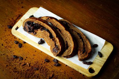 Lezzetli çikolatalı üzümlü ekmek. Çikolata parçalı dilimlenmiş ekmek. Kurabiye kağıdına tatlı koy. Ahşap masa arkaplanı.