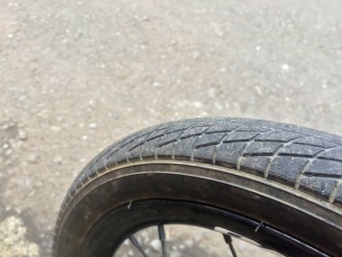Close up view of bicycle tire texture and wheel spokes against asphalt road background.
