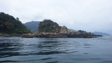 Egzotik ve çarpıcı, bulutlu gökyüzü, ada manzaraları ve mavi denizlerden oluşan az sayıdaki ağaçla kaplı kayalık bir çıkıntı şekli..