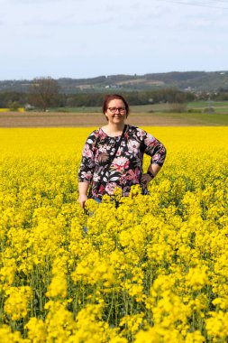Çiçek açan bir ırz tohumunun tarlasında bir kadın duruyor.