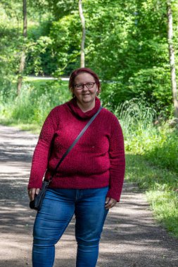 Güneşli bir yaz gününde, ormanda kızıl saçlı neşeli bir kadının portresi.