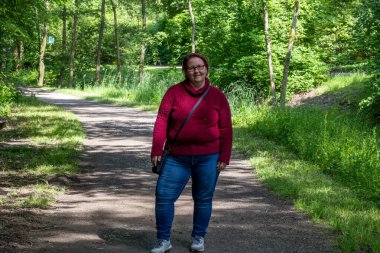 Güneşli bir yaz gününde, ormanda kızıl saçlı neşeli bir kadının portresi.