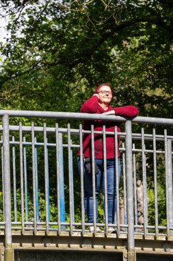 Güneşli bir yaz gününde, ormanda kızıl saçlı neşeli bir kadının portresi.